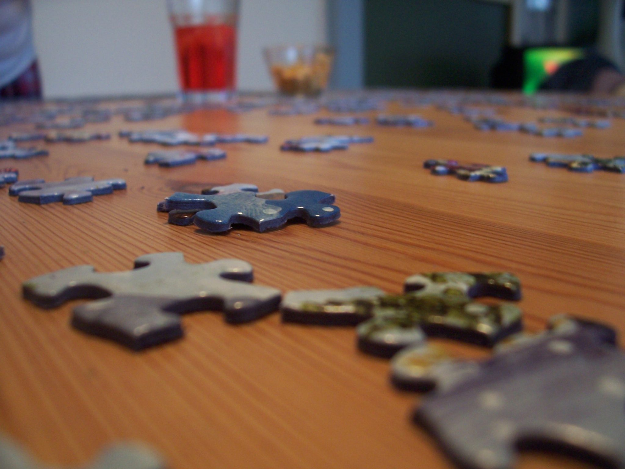Jigsaw puzzle pieces on a wooden table with drinks