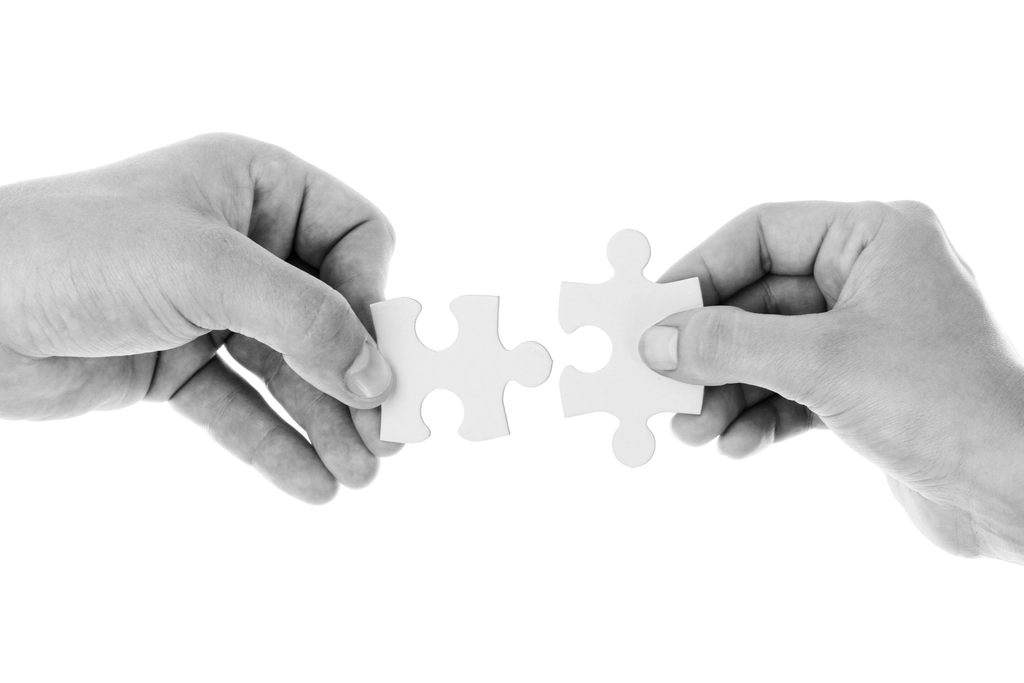 Two hands joining jigsaw puzzle pieces